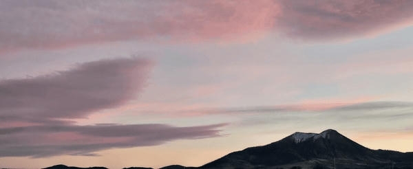 pink and purple sunset with a mountain filled with snow in the background